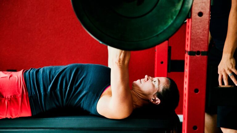 Woman performs bench press using a barbell