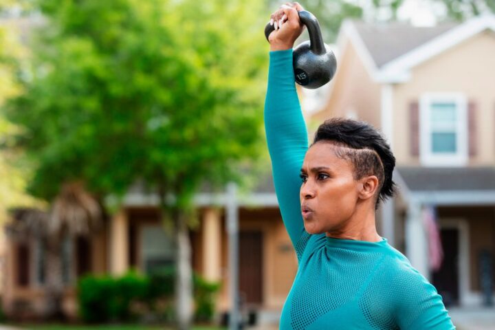 Woman presses kettlebell overhead